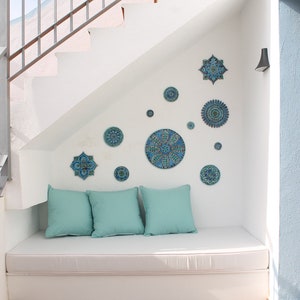 May include: A white bench with blue and green patterned cushions sits under a white staircase decorated with blue and green ceramic tiles.