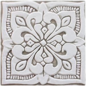 Puede incluir: Azulejo de cerámica blanca con un intrincado diseño floral en relieve. El azulejo tiene una superficie texturizada en relieve y una forma cuadrada.