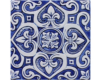 May include: A blue and white ceramic tile with a decorative floral pattern. The tile features intricate designs with a central flower motif and repeating patterns of leaves and swirls.