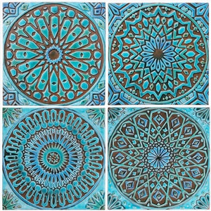 Op de afbeelding: Vier vierkante keramische tegels met ingewikkelde geometrische patronen in tinten blauw, groen en bruin. De tegels hebben een centraal cirkelvormig ontwerp met stralende lijnen en vormen.