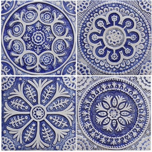 Op de afbeelding: Vier vierkante keramische tegels met ingewikkelde blauwe en witte bloemmotieven. Elke tegel heeft een ander ontwerp met een centraal motief omringd door kleinere details.