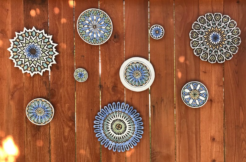 May include: A wooden wall with eight decorative ceramic plates with intricate geometric patterns in shades of blue, green, and yellow.