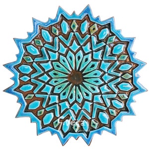 May include: A blue and brown ceramic wall tile with a geometric pattern. The tile is shaped like a star and has a raised design.