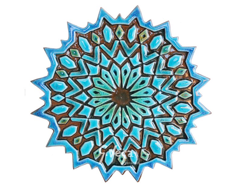 May include: A blue and brown ceramic wall tile with a geometric pattern. The tile is shaped like a star and has a raised design.