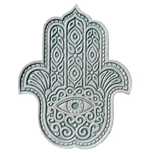 Op de afbeelding: Een witte keramische hamsa-hand met ingewikkelde blauwe en witte patronen. De hamsa-hand heeft een blauw oog in het midden.