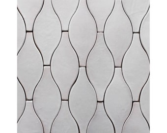 Pode incluir: Azulejos de cerâmica branca com forma de lágrima, dispostos em um padrão repetitivo. Os azulejos são brilhantes e têm uma superfície lisa.