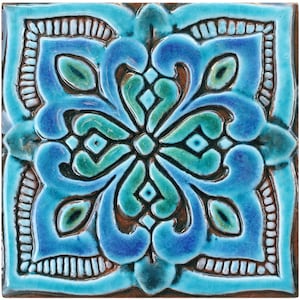 Könnte beinhalten: Eine quadratische Keramikfliese mit einem blauen, grünen und braunen floralen Design. Die Fliese hat eine erhabene, strukturierte Oberfläche.