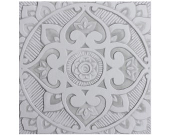May include: White ceramic tile with an intricate, embossed, mandala-like design. The tile features a circular pattern with a central flower and radiating petals.