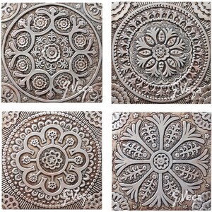 May include: Four square silver tiles with intricate embossed floral designs. Each tile features a different pattern with a central flower motif surrounded by smaller floral elements.