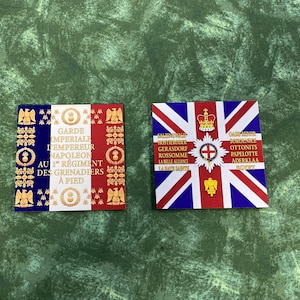 May include: Two square patches featuring historical military designs. The left patch displays the French tricolor flag with gold text reading GARDE IMPERIALE L'EMPEREUR NAPOLEON AU 1ER REGIMENT DES GRENADIERS A PIED. The right patch shows a British Union Jack.