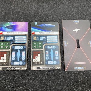 May include: Three Star Wars game cards. Two cards feature images of starships with text: "MC75 Ordnance Cruiser" and "MC75 Armored Cruiser." The third card is gray with a ship silhouette and text: "MC75 Armored Cruiser."