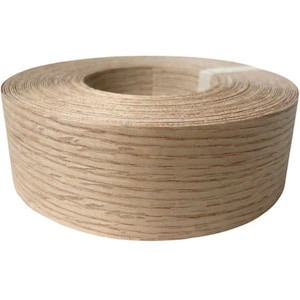 May include: A roll of light brown wood veneer edging. The veneer has a natural wood grain pattern with darker brown streaks. The roll is tightly wound, showing the edge of the veneer. The background is plain white.