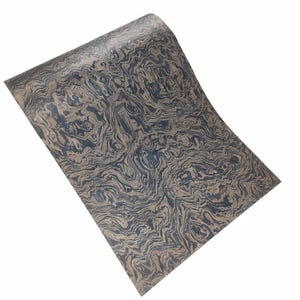 May include: A sheet of material with a swirling pattern in shades of brown and dark blue. The pattern resembles the natural grain of wood or the flow of water. The material is slightly curved, suggesting it is flexible.