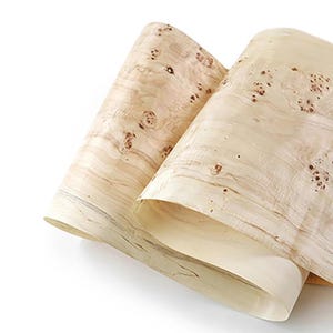 May include: Two sheets of light-coloured wood veneer, rolled up and overlapping. The wood has a natural grain pattern with small, dark brown knots and spots. The veneer appears smooth and flexible, with a slightly glossy finish.