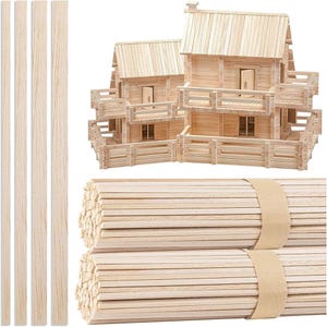 May include: Wooden building blocks and a model house made of the same material. The house has a roof, windows, and a balcony. Bundles of wooden sticks are also visible, secured with brown paper bands. The blocks and sticks are light brown.