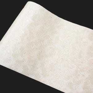 May include: A roll of off-white paper with a swirling, woodgrain-like pattern. The design features light beige and cream tones, creating a textured appearance. The paper is slightly curved, suggesting it is part of a larger roll.