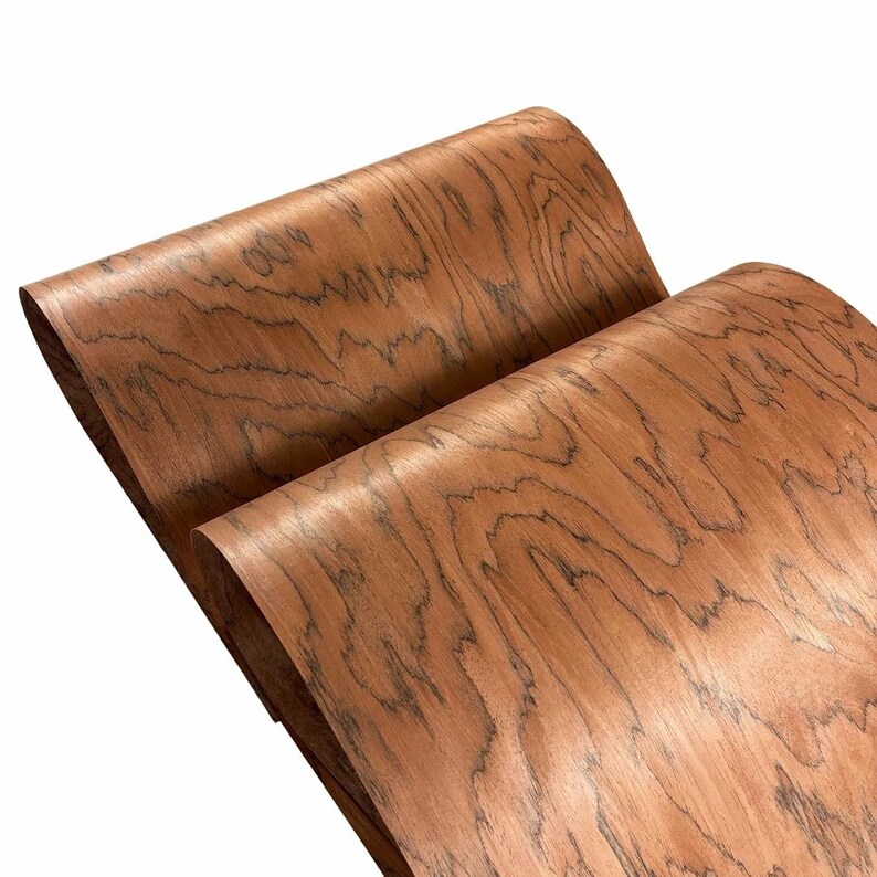 K&ouml;nnte beinhalten: Zwei Holzfurnierbl&auml;tter in einem r&ouml;tlich-braunen Farbton mit dunklen, wellenf&ouml;rmigen Maserungsmustern. Das Furnier ist gew&ouml;lbt und zeigt die nat&uuml;rliche Textur und Farbvariationen des Holzes. Das Bild ist gut beleuchtet und hebt die Details des Holzes hervor.