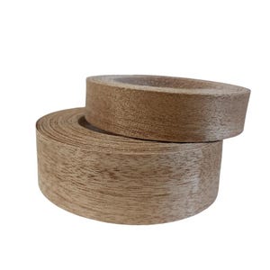 May include: Two rolls of wood veneer edging, one stacked on top of the other. The edging is a light brown color with a visible wood grain pattern. The rolls are tightly wound, showing the edge of the veneer.