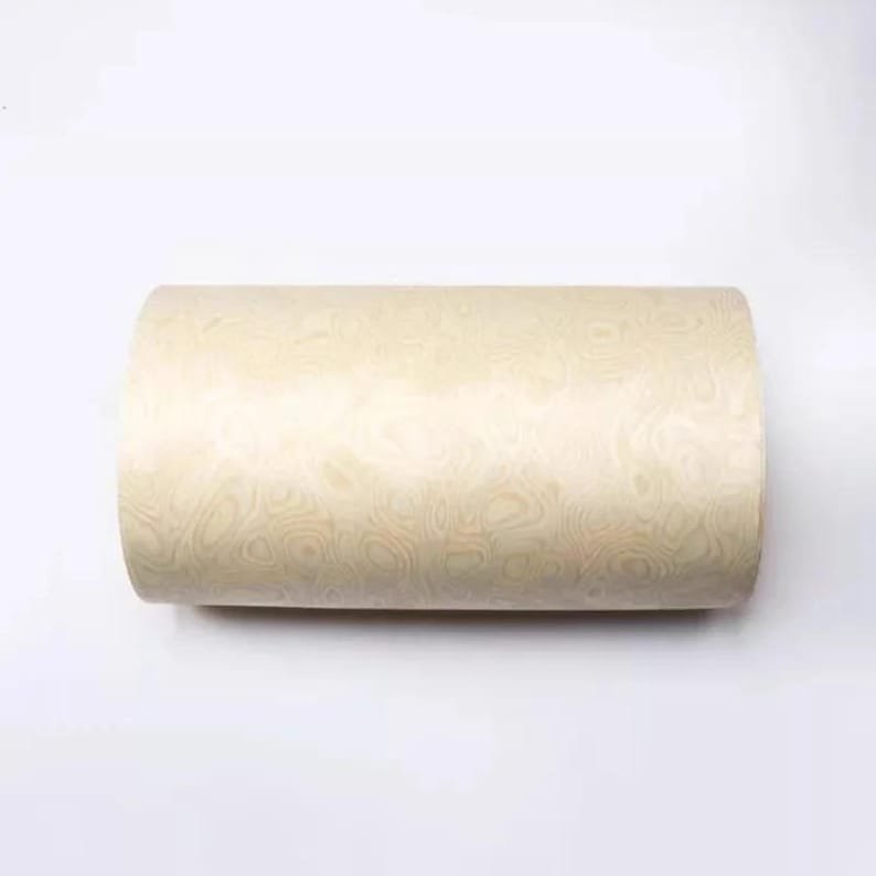 May include: A cylindrical object with a light beige, wood-grain pattern. The pattern features swirling, organic shapes in varying shades of beige and cream. The object appears to be made of wood or a wood-like material.