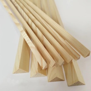 May include: A collection of unfinished wooden trim pieces, including triangular corner pieces and long, thin strips. The wood has a light, natural color and visible grain, suggesting it's ready for staining or painting. Ideal for woodworking projects.