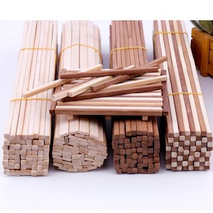 May include: Several bundles of wooden chopsticks in varying shades of brown, secured with yellow elastic bands. Some chopsticks are stacked, while others are arranged in a small, rectangular structure. The image showcases a variety of wooden chopstick designs.