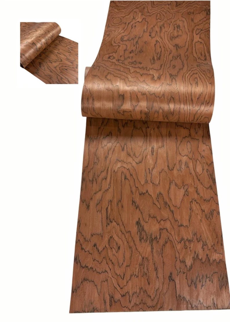 K&ouml;nnte beinhalten: Eine Rolle Holzfurnier mit einem satten, rotbraunen Farbton und einem auff&auml;lligen, wirbelnden Maserungsmuster. Das Furnier ist teilweise abgerollt und zeigt die komplizierten Details des nat&uuml;rlichen Designs des Holzes. Die Holzmaserung weist dunkle, wellenf&ouml;rmige Linien auf.
