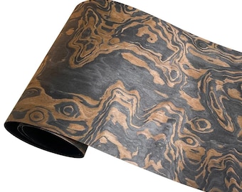 May include: A roll of wood veneer with a striking pattern of swirling dark gray and brown tones. The wood grain creates a natural, organic design. The veneer is rolled up, showing the dark underside.