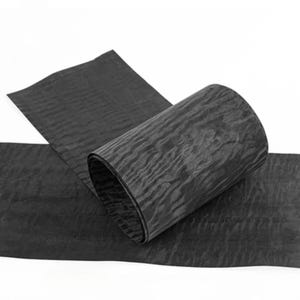 May include: A roll of black, textured material, partially unrolled against a white backdrop. The material displays a rippled, organic pattern. The unrolled section lies flat, while the rolled part stands upright.
