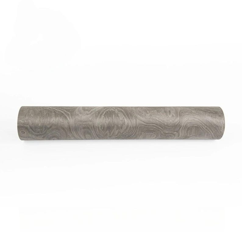 May include: A cylindrical object with a wood grain pattern in shades of gray. The object is a roll of wallpaper or decorative paper, likely for home decor projects. The surface has a swirling, naturalistic design.