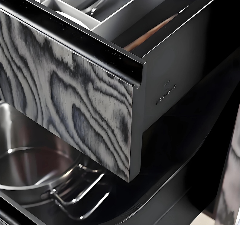 Puede incluir: Primer plano de un caj&oacute;n de cocina con un patr&oacute;n de vetas de madera en negro y gris. El caj&oacute;n est&aacute; abierto, revelando una olla y utensilios de acero inoxidable. El interior del caj&oacute;n es negro y se ve una cuchara de madera.