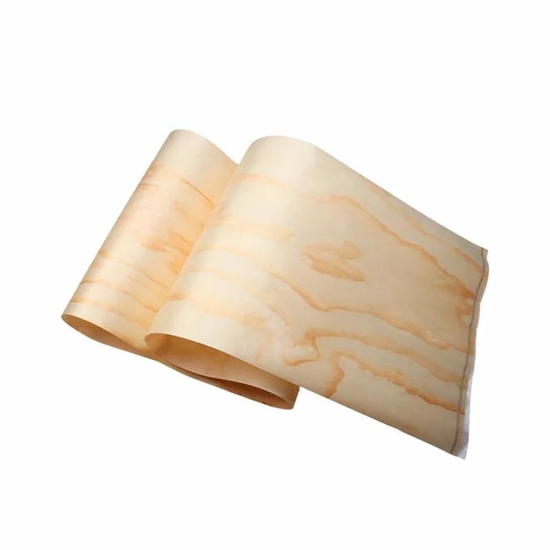 May include: Two sheets of light-colored wood veneer, rolled up and slightly overlapping. The wood grain is visible, with a mix of light and medium brown tones. The veneer appears smooth and flexible, suitable for various woodworking projects.
