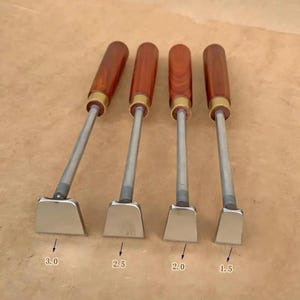 Può includere: Quattro smussatori per bordi in pelle con manici in legno e lame in metallo. Le lame sono contrassegnate con le misure 3,0, 2,5, 2,0 e 1,5. I manici sono marrone scuro e le lame sono argentate.