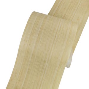 Può includere: Primo piano di una striscia di bambù chiara e strutturata, arricciata e stratificata. La venatura naturale del legno è visibile, con variazioni di tono dal beige chiaro al giallo pallido. La striscia appare flessibile e liscia.