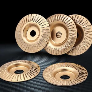 Puede incluir: Un conjunto de cinco discos de amolar circulares de metal dorado con una superficie texturizada de pequeños dientes elevados dispuestos en patrón radial. Cada disco tiene un orificio central y un centro rebajado para herramientas rotativas.