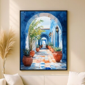 Op de afbeelding: Aquarel schilderij van een blauwe gewelfde gang met terracotta potten gevuld met planten. De gang leidt naar een verre boog, met een kleurrijke tegelvloer. Het kunstwerk is ingelijst in een zwart frame.