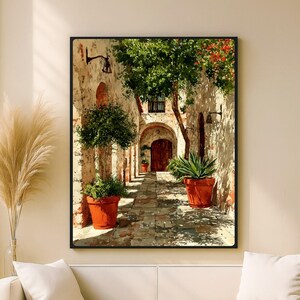 Peut inclure: Peinture encadrée représentant une ruelle ensoleillée dans un village européen. La scène présente des murs en pierre, un chemin en briques et des pots en terre cuite avec de la verdure. Une porte en bois et une entrée voûtée sont visibles au loin.