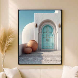 Puede incluir: Impresión enmarcada que presenta una escena arquitectónica serena. Una puerta turquesa con detalles ornamentados se encuentra en una entrada arqueada blanca. Dos macetas de terracota se asientan en un patio estampado. El fondo muestra una cúpula blanca y un cielo azul claro.