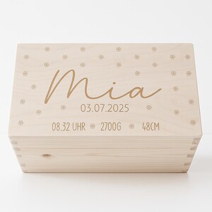 Può includere: Una scatola di legno color chiaro con il nome "Mia" in corsivo. La scatola è decorata con piccoli disegni floreali e include la data 03.07.2025, l'ora 08:32, il peso 2700g e l'altezza 48cm.