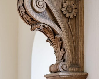 May include: A detailed, wooden corbel with intricate carvings. The corbel features floral and scroll designs, including a sunflower and stylized leaves. The wood has a warm, natural tone, and the corbel is mounted on a white wall.