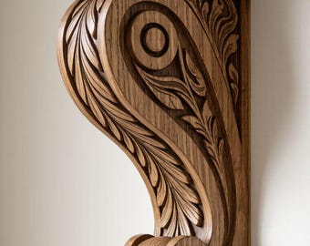 May include: A carved wooden corbel in a warm brown tone. The corbel features intricate leaf and scroll designs, with a detailed top and bottom. The wood grain is visible, adding to the natural aesthetic. This decorative element is suitable for interior design.