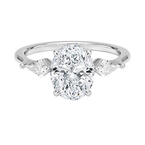 May include: A silver engagement ring with a large oval-cut diamond center stone and two smaller pear-shaped side stones. The ring has a classic, elegant design, perfect for a proposal or special occasion.