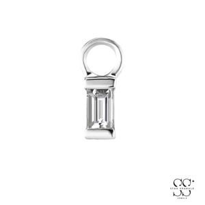 May include: A silver-toned pendant featuring a rectangular baguette-cut clear stone set in a vertical metal frame with a circular bail at the top. The piece has a polished metallic finish and a clean, structured design for a necklace or bracelet.