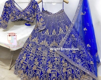May include: A royal blue, embroidered formal dress set. The set includes a long skirt, a cropped top, and a sheer scarf. The skirt and top are heavily embellished with gold-colored embroidery and sequins. The scarf has a matching border.