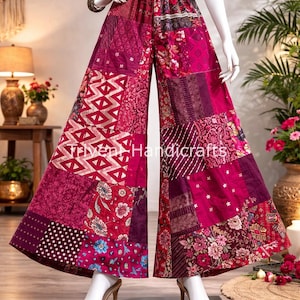 Op de afbeelding: Wijd uitlopende patchworkbroek in roze en bordeaux tinten. De broek heeft een mix van stoffen panelen met patronen, waaronder bloemen, geometrische en stippenpatronen. De tekst "Triven Handicrafts" is zichtbaar. De broek wordt op een mannequin getoond.