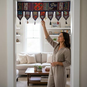 May include: A colorful, embroidered door valance with a dark blue border and decorative tassels. The valance features a patchwork design with various patterns and colors, adding a bohemian touch to the doorway. The valance is hung in a doorway.