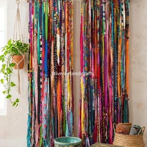 May include: A pair of floor-length curtains made from vertical strips of multicolored fabric in various patterns and textures, hanging from a wooden rod. The text Triveni handicrafts is visible in the center of the curtain panels.