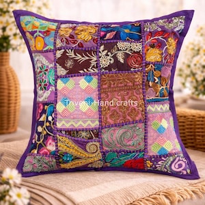 Puede incluir: Un cojín de patchwork cuadrado con un borde morado y una variedad de cuadrados de tela coloridos. El cojín tiene el texto "Beautiful Purple Patchwork Pillow" y "Triveni Handicrafts". Descansa sobre una manta beige.
