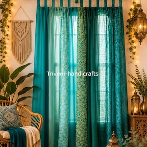 May include: A set of teal curtains with tab tops, featuring a mix of solid panels and panels with intricate floral patterns. The text Triveni-handicrafts is visible in the centre. The curtains are hung on a black rod with a decorative garland.