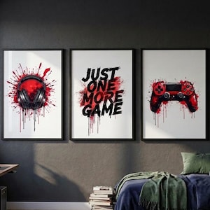 Peut inclure: Trois affiches murales encadrées représentant un casque noir, le texte "JUST ONE MORE GAME" en noir et une manette de jeu vidéo rouge. Chaque impression présente un fond blanc avec des éclaboussures de peinture rouge et noire.