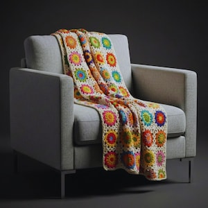 Könnte beinhalten: Eine farbenfrohe, handgefertigte Häkeldecke, die über einem grauen Sessel drapiert ist. Die Decke zeigt ein sich wiederholendes Blumenmuster in leuchtenden Farben wie Rot, Gelb, Blau und Grün. Der Hintergrund ist cremefarben, der Sessel hat Metallbeine.